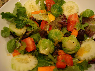 Mixed greens topped with vegetables and dressing in white bowl