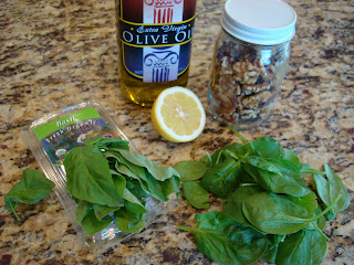 Pack of basil, spinach, olive oil, lemon and walnuts on countertop