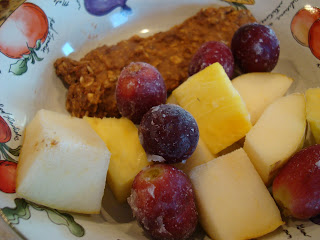 Slice of Breakfast Cookie, Diced Pineapple, Pears and Grapes in pattered bowl