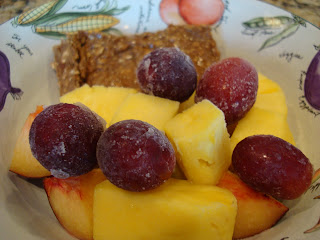 Bowl full of sliced Breakfast Cookie, grapes, plums and Mango