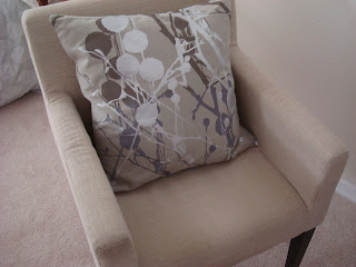 Tan chair with neutral accent pillow on chair