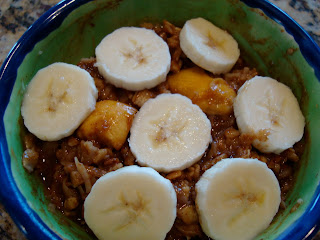 Oats topped with sliced banana and mangos in blue and green bowl