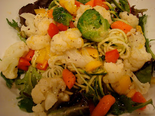 Spiralized zucchini noodles topped with vegetables and dressing in white bowl