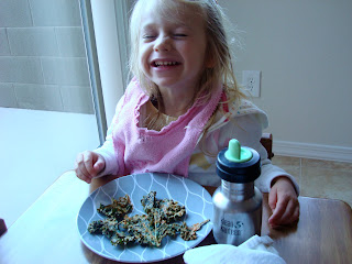 Young girl smiling at table eating Kale Chips
