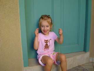 Young girl wearing pink sitting in front of blue door