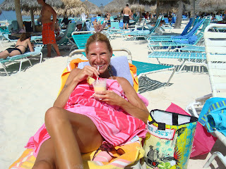Woman on lounger drinking a drink and smiling on beach