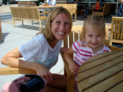 Woman crouching next to young girl at table smiling