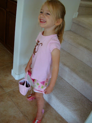 Young girl standing in front of stairs holding pink bag 