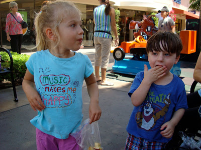 Young girl and boy standing eating snacks