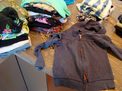 Various piles of clothes on countertop
