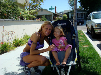 Woman in workout close squatting next to young girl in stroller