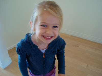 Young girl smiling in blue zip up sweatshirt