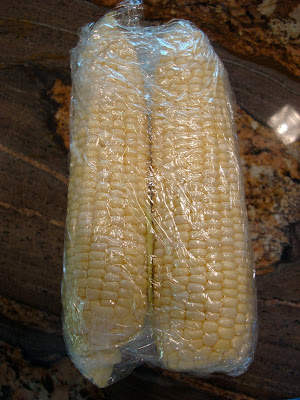 Two ears of corn wrapped in plastic wrap