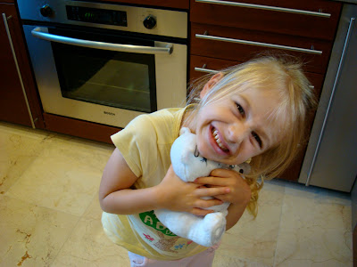 Little girl in kitchen hugging toy