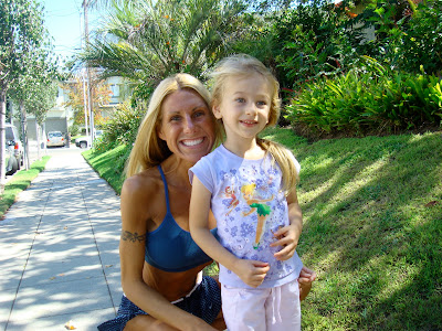 Woman in workout close with arm around young girl on sidewalk smiling