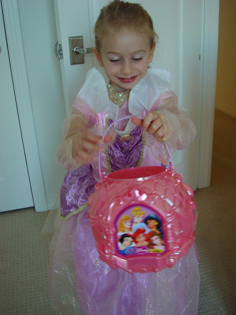 Young girl in halloween costume holding trick-or-treating bucket