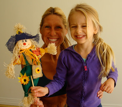 Woman standing behind young girl holding scarecrow decoration