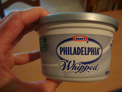 Hand holding container of Whipped Cream Cheese