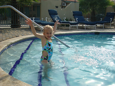 Young girl with arms over head on steps in pool