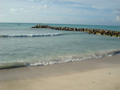 Waves coming up onto beach with rocks going out into ocean