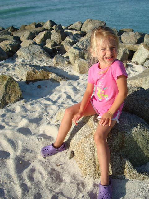 Young girl sitting on rocks on beach