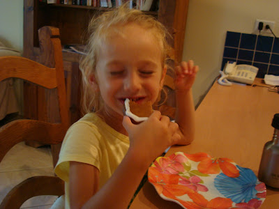 Young girl smiling while putting portion of gingerbread man up to mouth