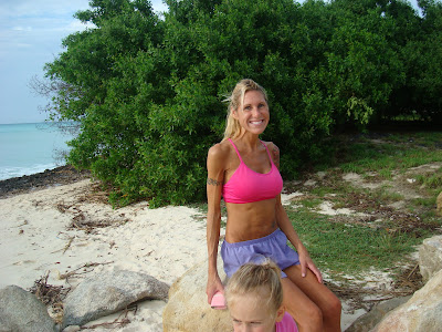 Woman sitting on rock on beach in front of trees with young girl