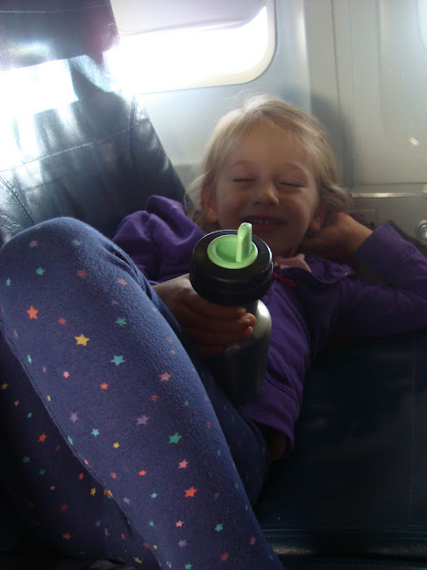 Close up of young girl laying in plane seat pretending to be sleeping