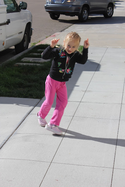Young girl dancing with arms up on sidewalk