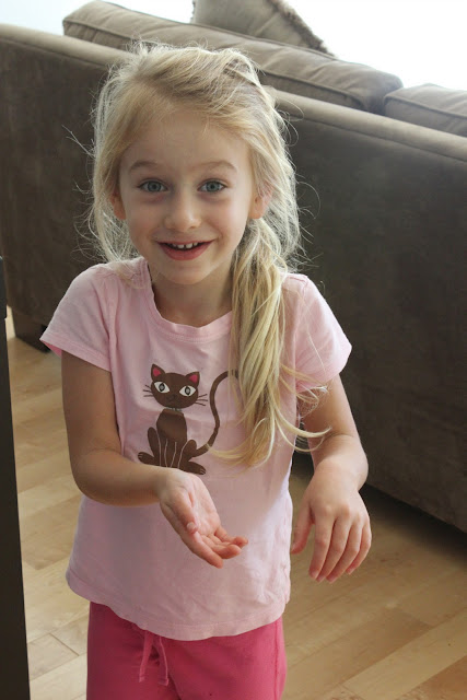 Young girl standing behind couch with hair in ponytail