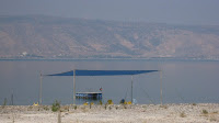 View of the Sea of Galilee with far shore in the background and a child jumping off a raft into the water