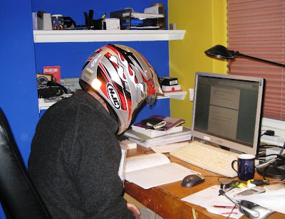 Mr A reading at his desk wearing a full face crash helmet