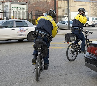 cops talking on cell phones while riding bikes
