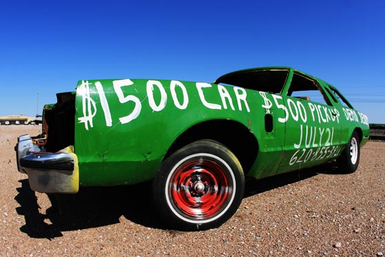 long, green demolition derby car parked off the highway somewhere in ...