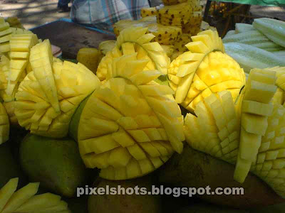 photographs of mangoes sliced in designs from street side fruits sellers in kerala india,sliced fruits in streets, street fruit merchants, fruits sold in pulling carts, unthu vandy pazha kachavadam, kerala mangoes, mango fruit uses and medicinal value, closeup fruits photography
