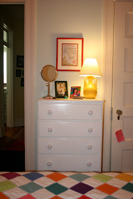 white dresser with yellow lamp