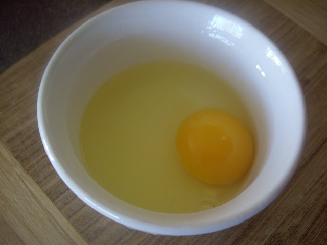 A bowl with a cracked egg in it. 