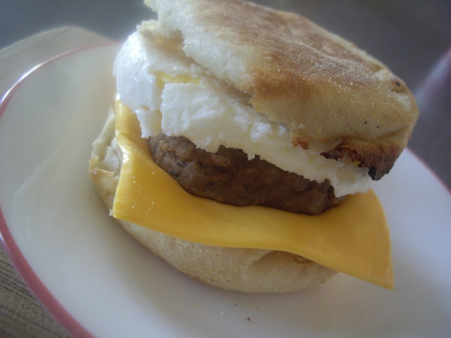 A display of a sausage patty in between a slice of cheese, a fried egg and a toasted English muffin.