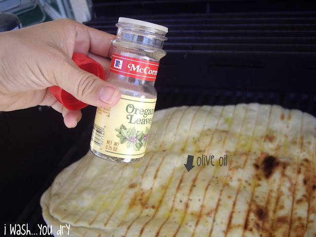 Oregano leaves sprinkled on a grilled pizza crust. 