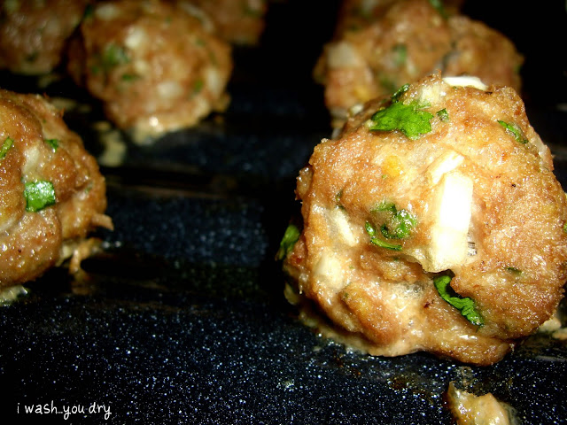 A close up of baked meatballs on a pan. 