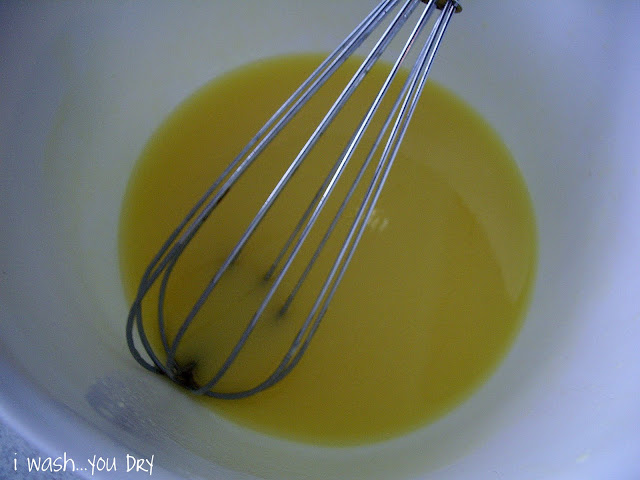 A wire whisk stirring a liquid in a bowl. 