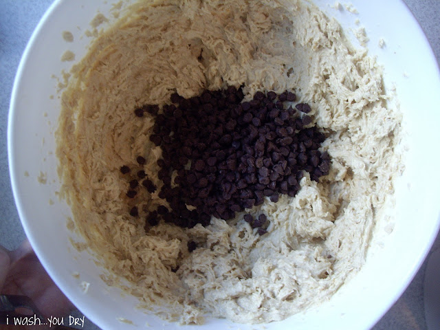 Chocolate chips added to a bowl of cookie mix. 