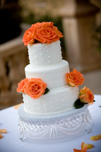 Three tier round wedding cake in white with edible pearls texture and orange