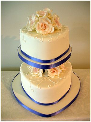 Two tier heart wedding cake with peach colored sugar roses and deep blue