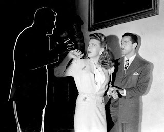 From right to left: Alan Curtis, Evelyn Ankers and the outline of Jon Hall in a publicity still for The Invisible Man's Revenge.