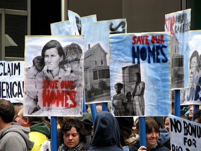 protesters with signs that say that they do not want to lose their homes
