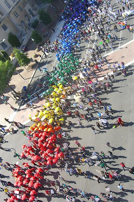 people marching with colored umbrellas that made a rainbow flag pattern from above