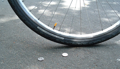 Image of coins near a bicyle tire on the street