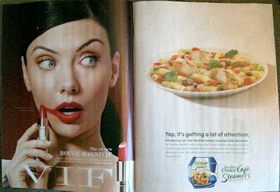 Magazine with two full-page ads. Left ad is a pretty model accidentally putting lipstick onto her right cheek because she's so distracted by what's going on on the other page. But the other page is another ad, this time for a frozen diet dinner.