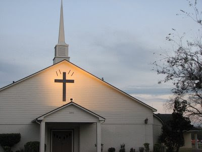 Suburban church with a cross over the door. Quotation marks around the cross.